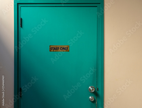 Staff Only Sign on a Green Wooden Door with wall background