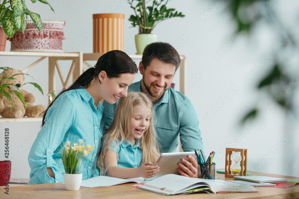 Father, mother and their daughter are smiling while spending time together. A day with family. Young happy couple with child are studying with the tablet. Education, studying and knowledge sharing Father, mother and their daughter are smiling while spending time together. A day with family. Young happy couple with child are studying with the tablet. Education, studying and knowledge sharing