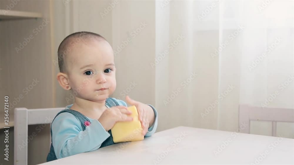 Little hungry girl with short hair on her head eating yellow cheese at the table Little hungry girl with short hair on her head eating yellow cheese at the table