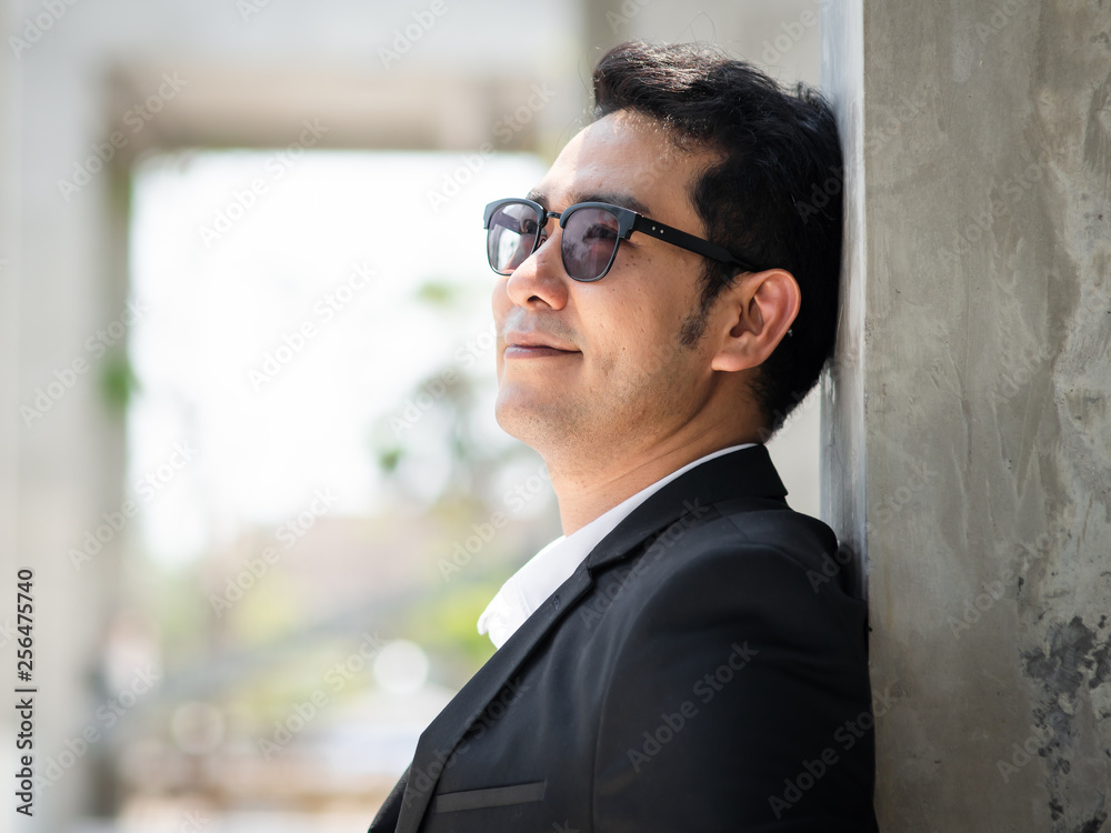 Happy Asian businessman standing in city with building background. Happy Asian businessman standing in city with building background.