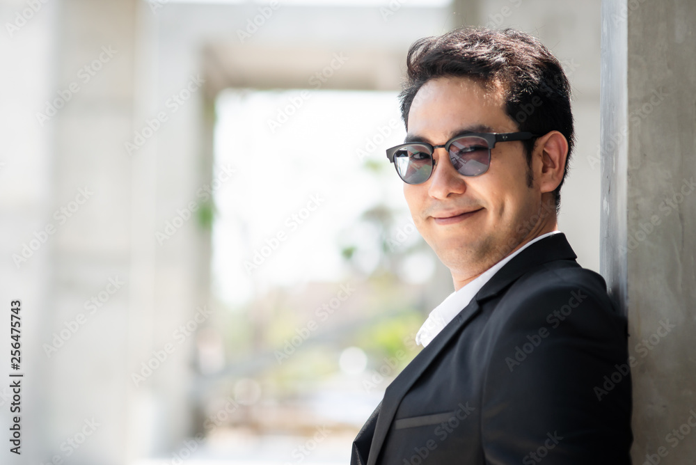 Happy Asian businessman standing in city with building background. Happy Asian businessman standing in city with building background.