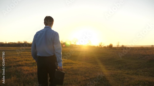 Business man with briefcase goes on beautiful sunset after working day.