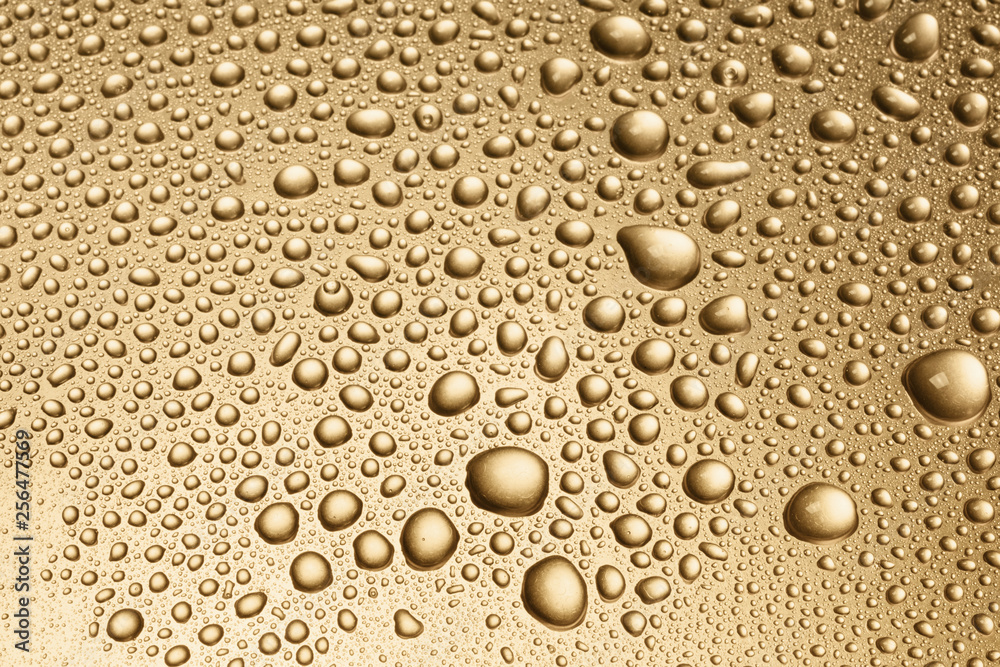 Shiny water drops on golden metal surface, background