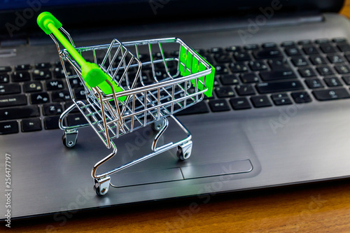Online shopping concept. Small shopping cart on laptop keyboard