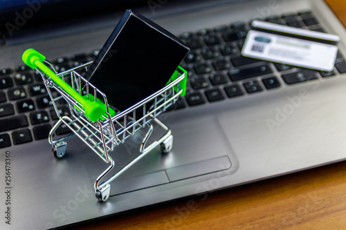 Online shopping concept. Small shopping cart with box and credit card on laptop keyboard
