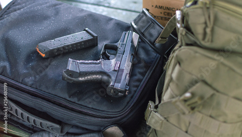 A black gun lying in the military environment next to ammo and backpack. Shooting range.