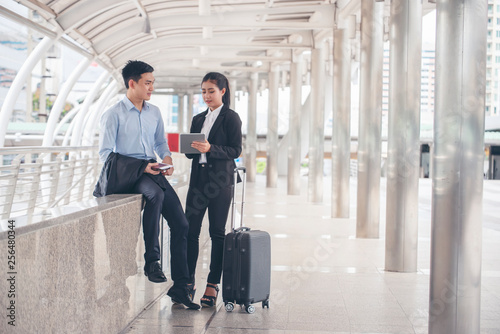 Business man and woman Dragging suitcase luggage bag,walking to passenger boarding in Airport,travel to work.Asian tourist menand women wearing black suit pull trolley bag. Business travel concept