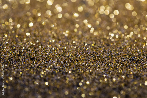 twinkling golden glitter falling on a flat surface lit by a bright spotlight (3d illustration)