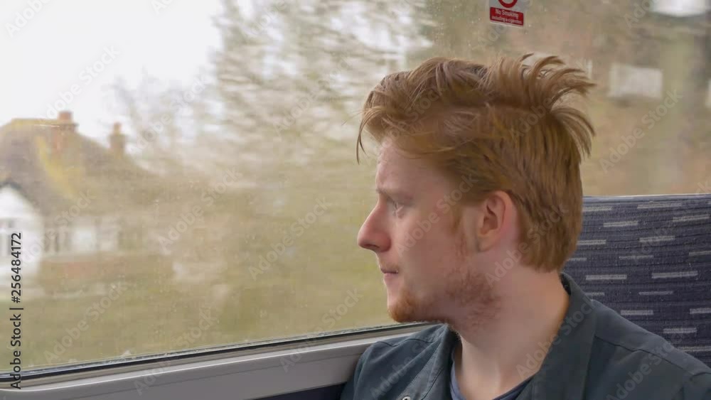 Young Man Stares Out Train Window At Passing Towns.