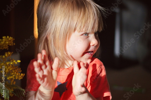 little girl claps her hands and smiles of joy on a sunny spring day