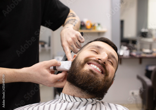 Client during beard shaving in barber shop 