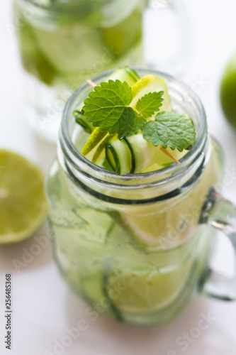 a glass of water, mint, lime and cucumber.