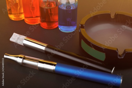 Canvastavla Vaping devices lying near ashtray and bottles with vape liquid on black matte su