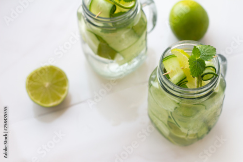 glasses with water, ice, mint, lime and cucumber and place for text on a white background.