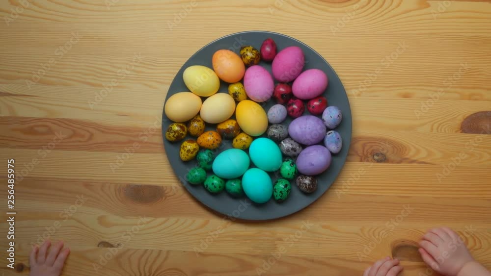 children's hands taking multi-colored Easter eggs from a grey plate children's hands taking multi-colored Easter eggs from a grey plate