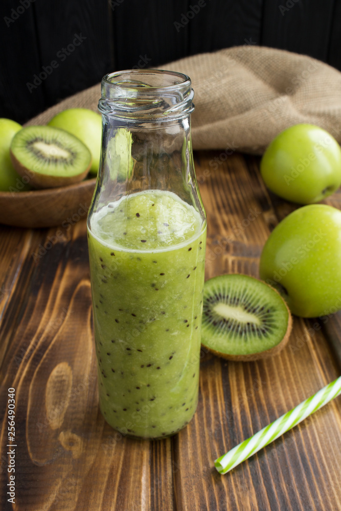 Smoothies with kiwi and green apples in the glass bottle on the rustic wooden background Smoothies with kiwi and green apples in the glass bottle on the rustic wooden background