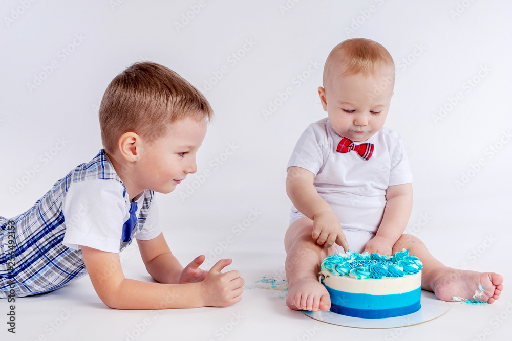 The child eats cake with his hands. Birthday child. Two brothers. Infant baby. The boy runs his hands into the cake. Children share the cake. Birthday celebration. Festive cake. The child eats cake with his hands. Birthday child. Two brothers. Infant baby. The boy runs his hands into the cake. Children share the cake. Birthday celebration. Festive cake.