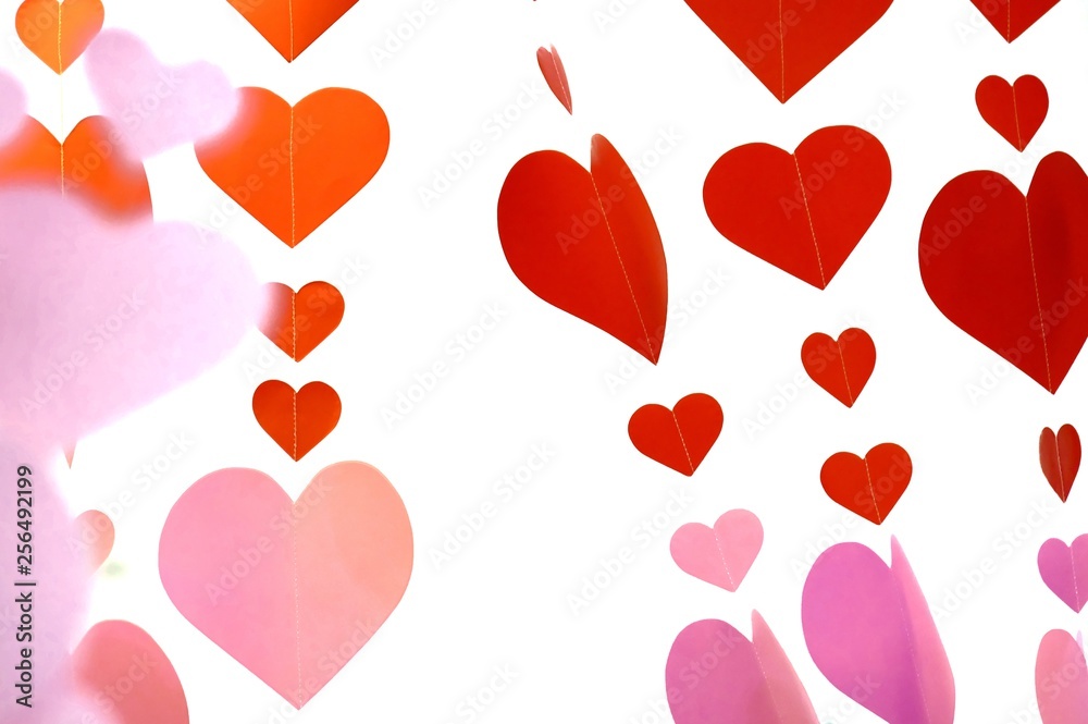 Red orange pink paper heart signs hanging on a strings on white isolated background for Valentine's Day backdrop 