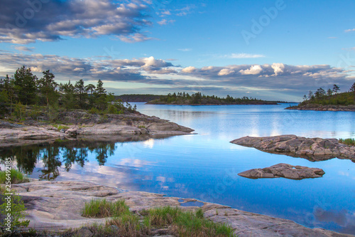 Cove on the lake. Northern nature. Clouds fly over the water. Rocky coast. Reflection of the sky in the water. Journey to the wild. Karelia. The nature of Russia.