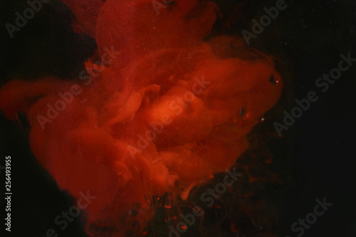 spots of red paint in water dark background texture closeup macro