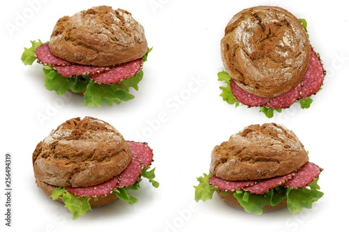  whole-grain bun topped with salad and salami sausage - freshly baked whole grain bun breakfast isolated on white