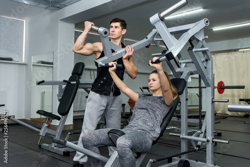 Coach training young and beautiful woman in gym