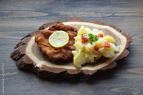 Weiner schnitzel with potato salad on a wooden background