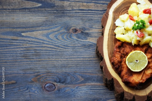 Weiner schnitzel with potato salad on a wooden background