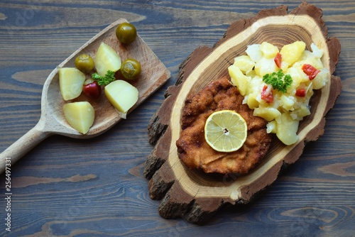 Weiner schnitzel with potato salad on a wooden background