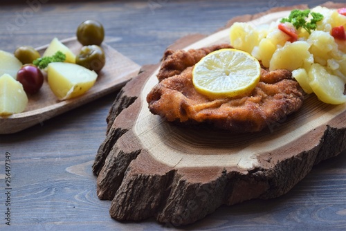 Weiner schnitzel with potato salad on a wooden background