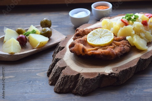 Weiner schnitzel with potato salad on a wooden background