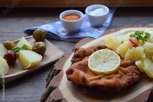 Weiner schnitzel with potato salad on a wooden background