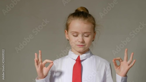 girl in a white blouse with a red tie meditates