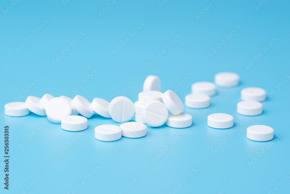 White pills or capsules on a blue background with copy space. White pills or capsules on a blue background with copy space.