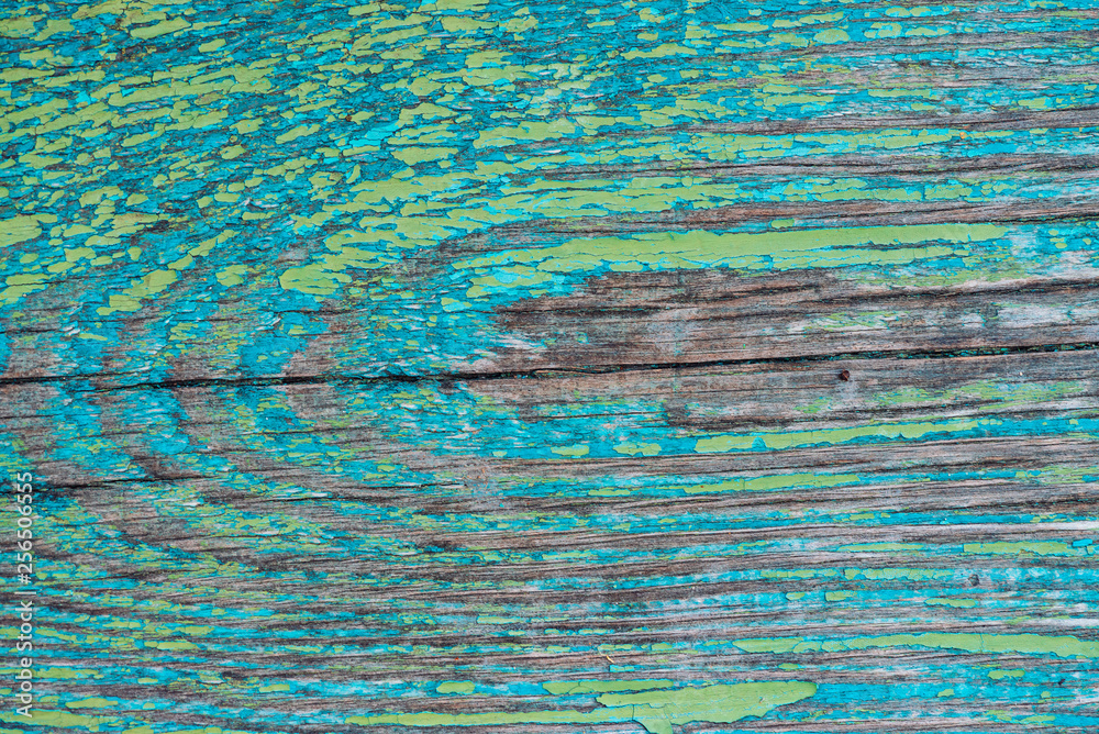 Old wooden painted rustic wall with blue green flaky dye. Faded wood plank close-up. Peeling paint on board. Scratched rough wooden texture. Imperfect wood surface. Background with weathered paint.