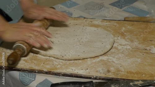 Female hands roll out dough with rollinpin on wooden board