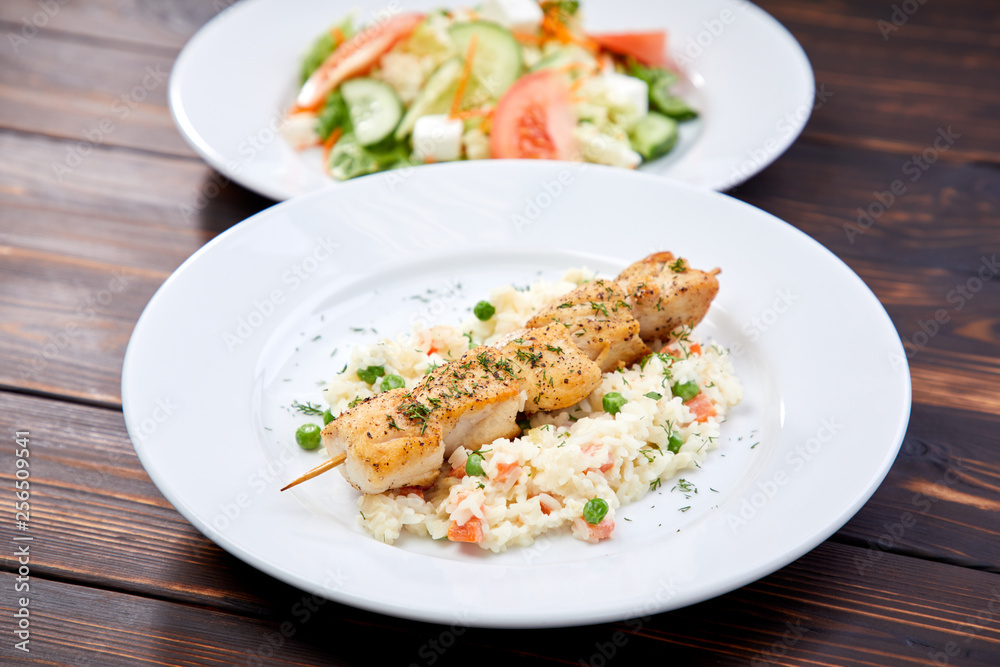 chicken kebab with rice and vegetables on the wooden background