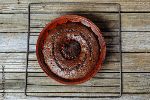 Chocolate cupcake on an iron grid on a wooden table.