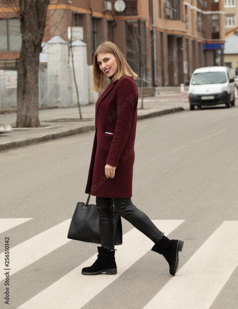 Fototapeta premium Full body portrait of young woman crossing street