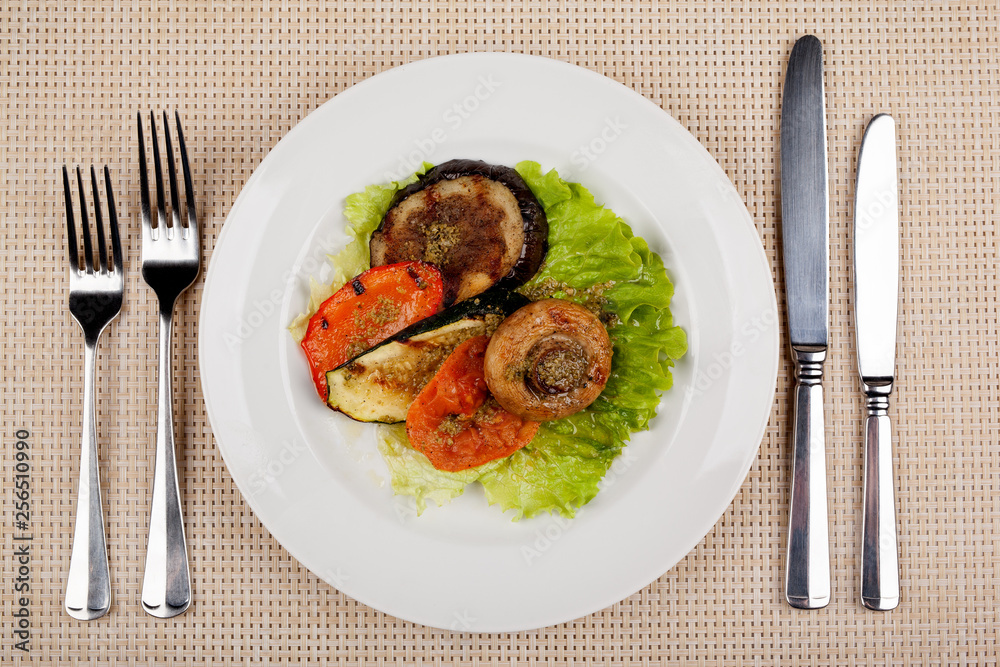Fried mushroom champignon, eggplant, tomato and green leaf lettuce on a white round plate. Fried mushroom champignon, eggplant, tomato and green leaf lettuce on a white round plate.