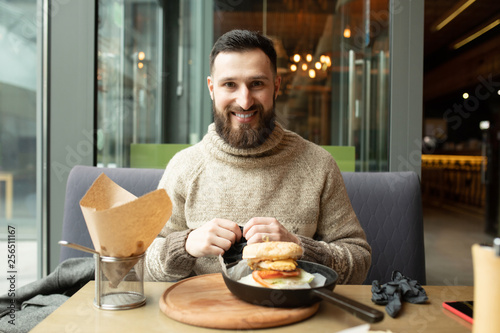 Happy man eating burger in restaurant