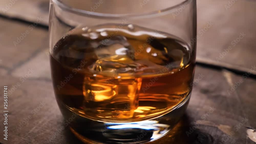 Golden whiskey rotating in the glass. With ice cubes. Golden whiskey rotating in the glass. With ice cubes.