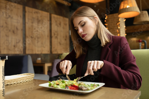 Blonde woman eating green healthy tasty eco salad on city cafe