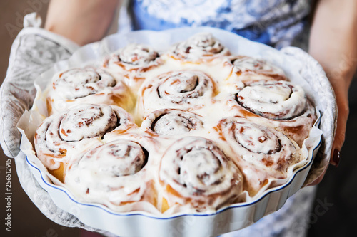 Cinabon rolls with cream cheese on the baking form in the women's hands photo