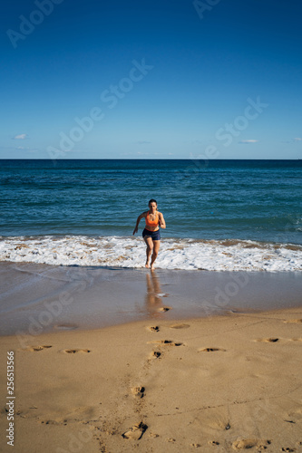 Fitness young woman running on the beach during summer holiday