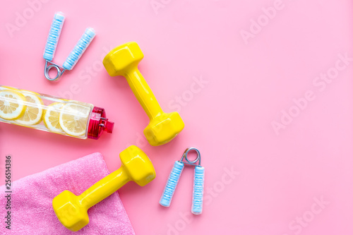 workout with bars, bottle of water and wrist builder pink background top view mockup