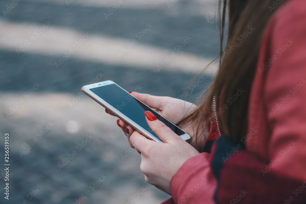 Female hands holding a mobile phone outdoors