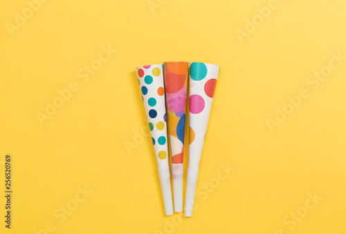 Party horn noise makers on a yellow paper background photo