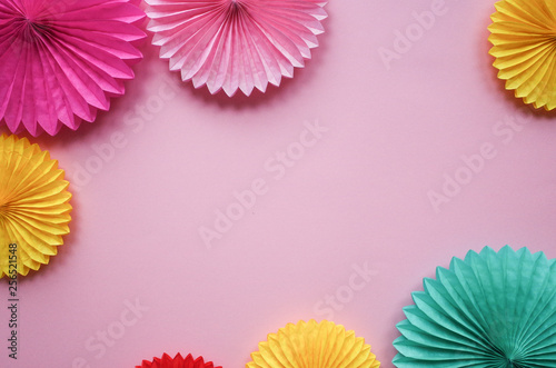 Different paper flowers on pink table top view. Festive or party background. Flat lay style. Copy space for text. Birthday greeting card.