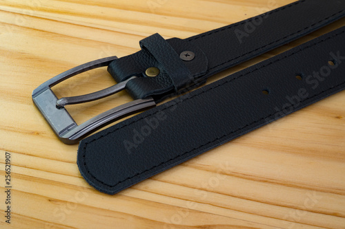 fashion leather belt color black on wooden background with steel metal buckle 